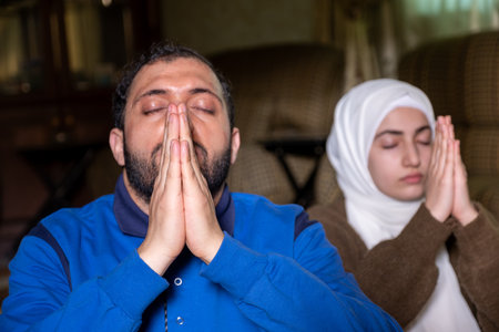 muslim couples praying together asking allah for mercy and forgiveness ,wearing casual clothes in homeの写真素材