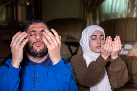 muslim couples praying together asking allah for mercy and forgiveness ,wearing casual clothes in homeの写真素材