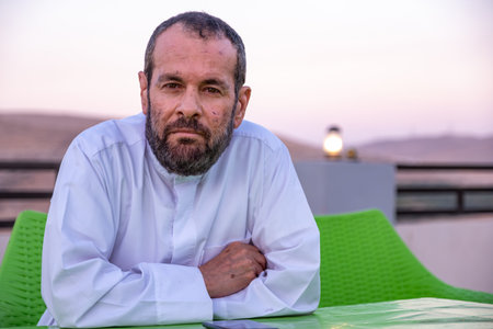 Portrait of arabian old arabian man sitting on chair have facial expression of sadness