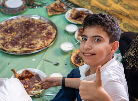 Portrait Of boy making gesture with hand while eating with family and smileの写真素材
