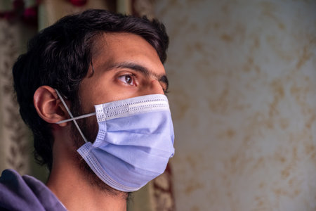 Male wearing mask and praying to protect him from diseases and help him being wellの写真素材