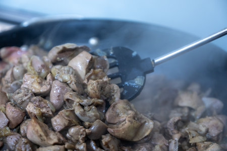 Sizzling Diced Meat in a Frying Pan on the Stove with a Spatula and Steam
