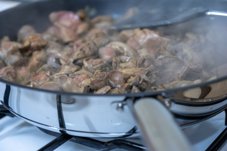 Sizzling Diced Meat in a Frying Pan on the Stove with a Spatula and Steamの写真素材