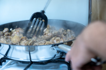 Sizzling Diced Meat in a Frying Pan on the Stove with a Spatula and Steamの写真素材