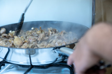 Sizzling Diced Meat in a Frying Pan on the Stove with a Spatula and Steamの写真素材