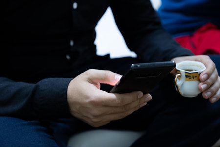 Man holding coffee cup with mobile phone in handの写真素材