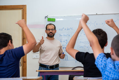 Children's in school so excited with their teacher and raising their hands to answer the teacher questionsの写真素材