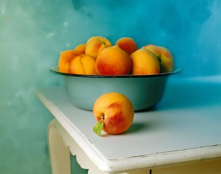 group of Peaches in blue old bowl and one peach on the white old tableの写真素材