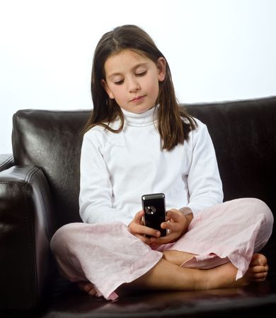 young girl and cell phone on a sofaの写真素材