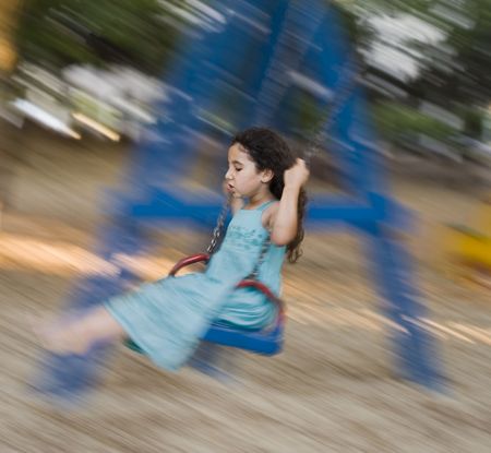 girl in blue dress on a swing with motion blurの写真素材
