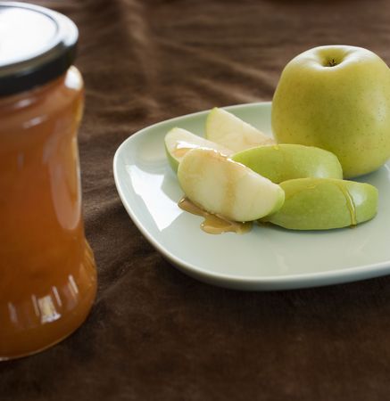 Honey drippin on a green apple slice with jarの写真素材