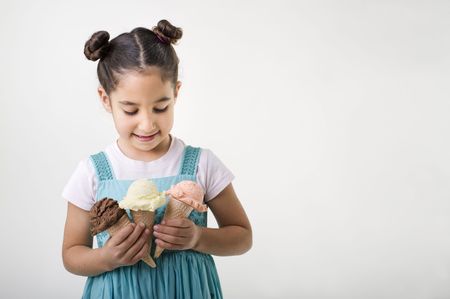 little girl holding three cones with chocolate, vanila and strawberry ice cream scoops の写真素材