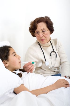 senior woman doctor checking temperature on child penitent at homeの写真素材