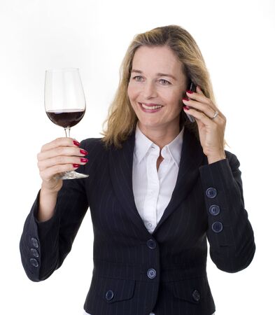 Smiling European business women in her 40's talking on the phone and having a glass of wineの写真素材
