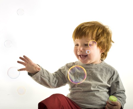 A little boy blowing soap bubbles on whiteの写真素材