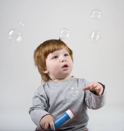 little redhead boy playing with soap bubbelsの写真素材