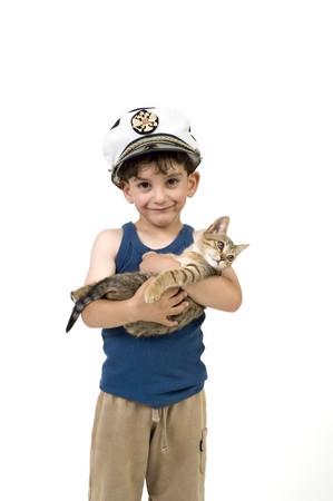 young boy with a captain hat holding a kittenの写真素材