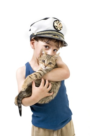 young boy with a captain hat holding a kittenの写真素材