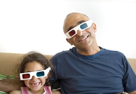 Father and daughter watching television in 3D wearing red and blue glassesの写真素材