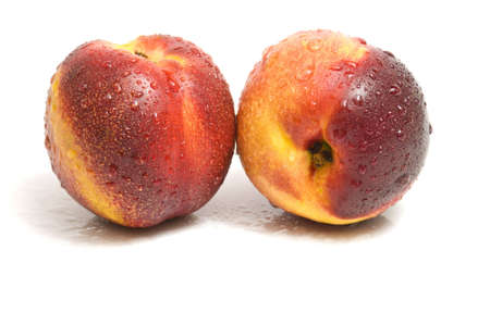 close-up on two fresh organic nectarines, isolated on whiteの写真素材