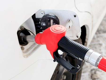 White car at gas station being filled with fuel 