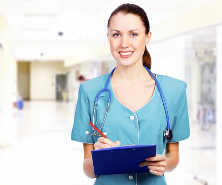 Smiling female medical doctor with clipboard in a corridor of a hospital の写真素材