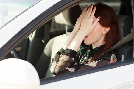Troubles on the road, Girl hides face in hands while in a car