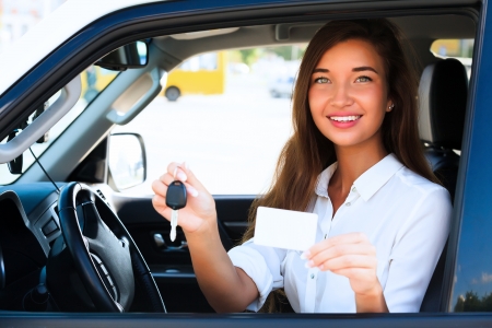 girl in a car showing a key and an empty white card
の写真素材