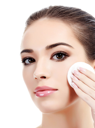 Beautiful woman using a cotton pad to remove her makeup. の写真素材