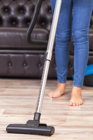 Housewife with a vacuum cleaner cleans the room in the houseの写真素材