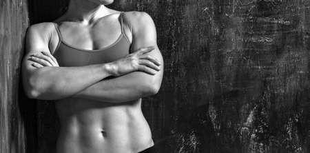 Strong muscular woman is posing against grunge wallの写真素材
