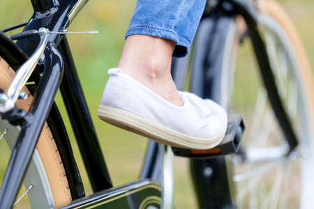Female foot wearing white shoe on a pedal of a bicycleの写真素材