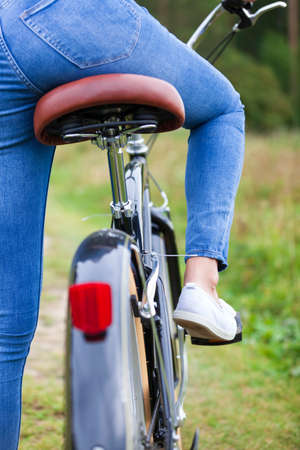Woman wearing blue jeans sitting on a black bicycleの写真素材