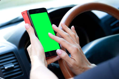 woman driver with a smartphone in her hands while driving.
