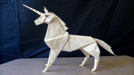 Unicorn origami made of paper on a black background.の素材