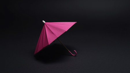 Pink paper umbrella on black background with copy space. Minimal conceptの素材