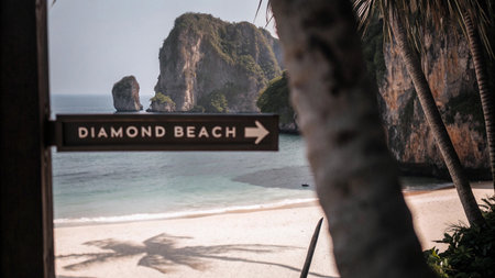 A sign points the way to the idyllic Diamond Beach, framed by lush tropical foliage, turquoise waters, and dramatic limestone cliffs. This stunning destination is a true paradise for travelers seeking natural beauty and serene escape.の素材