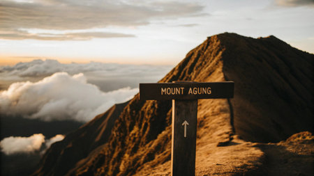 A weathered sign points the way to Mount Agung volcano summit in Bali, Indonesia, promising an adventurous trek through scenic landscapes and clouds.の素材