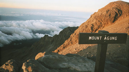 Experience the majestic Mount Agung summit in Bali, Indonesia. This captivating image shows a weathered peak sign overlooking an expansive, stunning cloudscape, a truly breathtaking natural panorama from high above the island.の素材