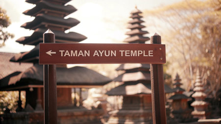 A wooden signpost warmly lit by sunlight points visitors toward the ancient Taman Ayun Temple in Bali, revealing its beautiful tiered roofs and cultural heritage.の素材