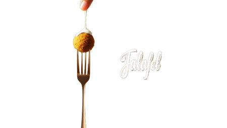 Golden falafel ball on a fork with sauce. This minimalist food photography features a clean white background, perfect for showcasing delicious plant based cuisine and healthy mediterranean meal ideas.の素材