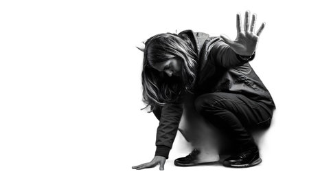 A captivating black and white image displays a person crouching in a deep, emotive pose. This monochrome photograph evokes feelings of contemplation and vulnerability through its dramatic contrast and unique composition. Its an artistic study of human forの素材