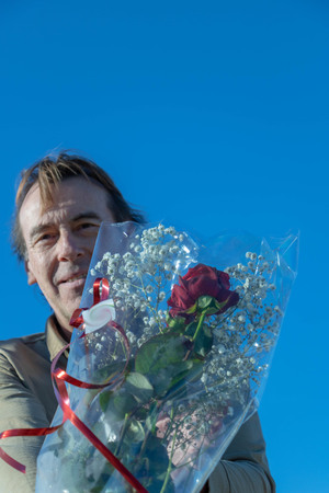 Man holding in front of him the bouquet of flowers that he will offerの写真素材