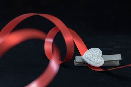White ceramic heart and red ribbon, intimate photo on black backgroundの写真素材