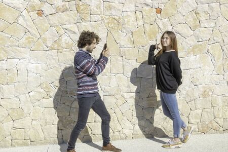 Young man taking a picture of his girlfriend posing in front of the camera