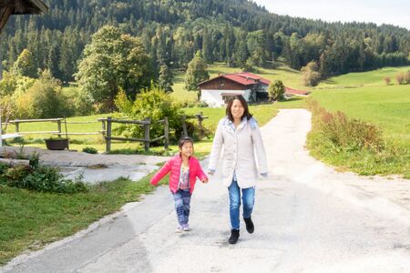 Family walk with Mom - Eurasian girl French and Chinese Metis walking with her Chinese mother in the countryside on the edge of forest in Franche Comtéの写真素材