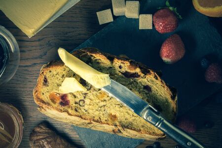Close-up breakfast with bread with dried fruits and cereals orange honey red fruits and a butter knife for spreading croissant - vintage filterの写真素材