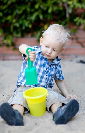 adorable toddler playing with shovel and bucket in the sandboxの写真素材
