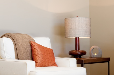 cozy seat with throw and pillow, lamp and burning candle in the backgroundの写真素材