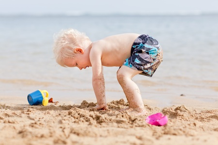 adorable toddler playing in sand on a tropical beach